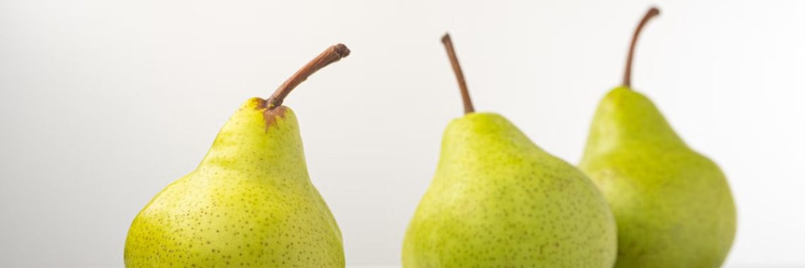 Three organic pears on a reflective white surface showcasing freshness and simplicity.